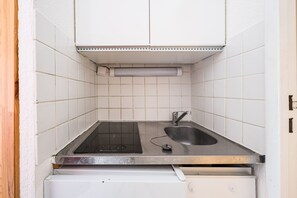 Eine kleine Küche mit eingebautem Herd, Spüle und einer weißen, gefliesten Rückwand.