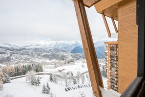 Eine verschneite Berglandschaft mit Blick auf ein Gebäude mit Holzbalkonen und einem Balkon.