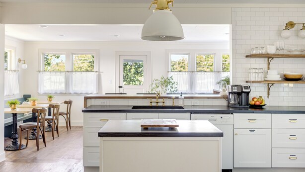 Een ruime keuken met een groot kookeiland, witte kastjes en een hanglamp.