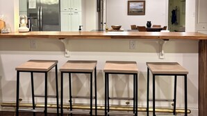 Een moderne keuken met een centraal eiland, barstoelen en een hangende pendelverlichting.