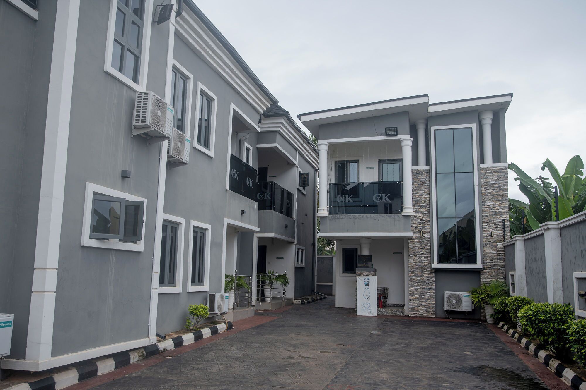 A multi-story residential building with balconies, air conditioning units, and a paved courtyard.