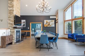 A dining area with a long table, blue chairs, a chandelier, and artwork on the walls. - Large Chalet 10 Bedrooms 14 Beds-Large Hot Tubs-Fire Pit-Projector, Games Room (Blue Mountains)