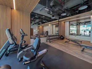 A modern gym with stationary bikes, dumbbells, and a bench. - Luxurious with Nature & 5 Star Amenities (Dubai)