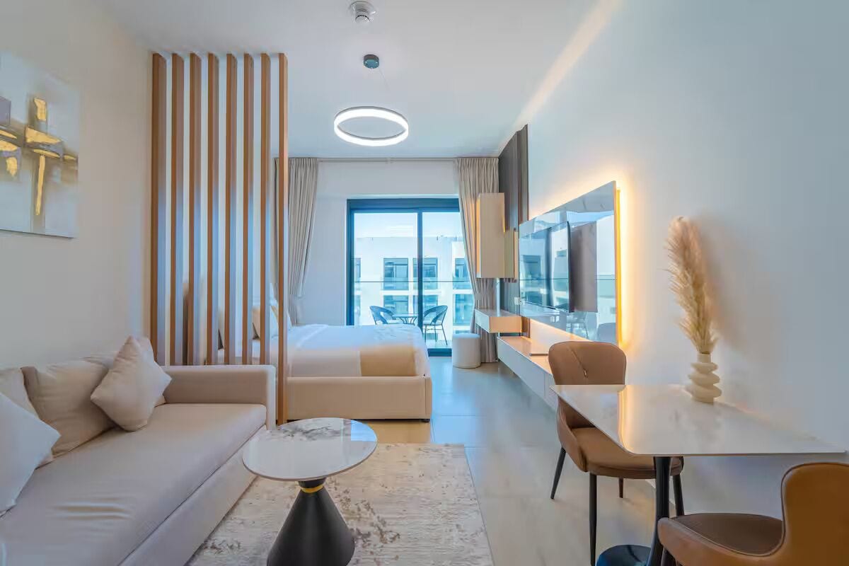 Quarto de hotel moderno com uma cama grande, um sofá, área de jantar e vista para a cidade.