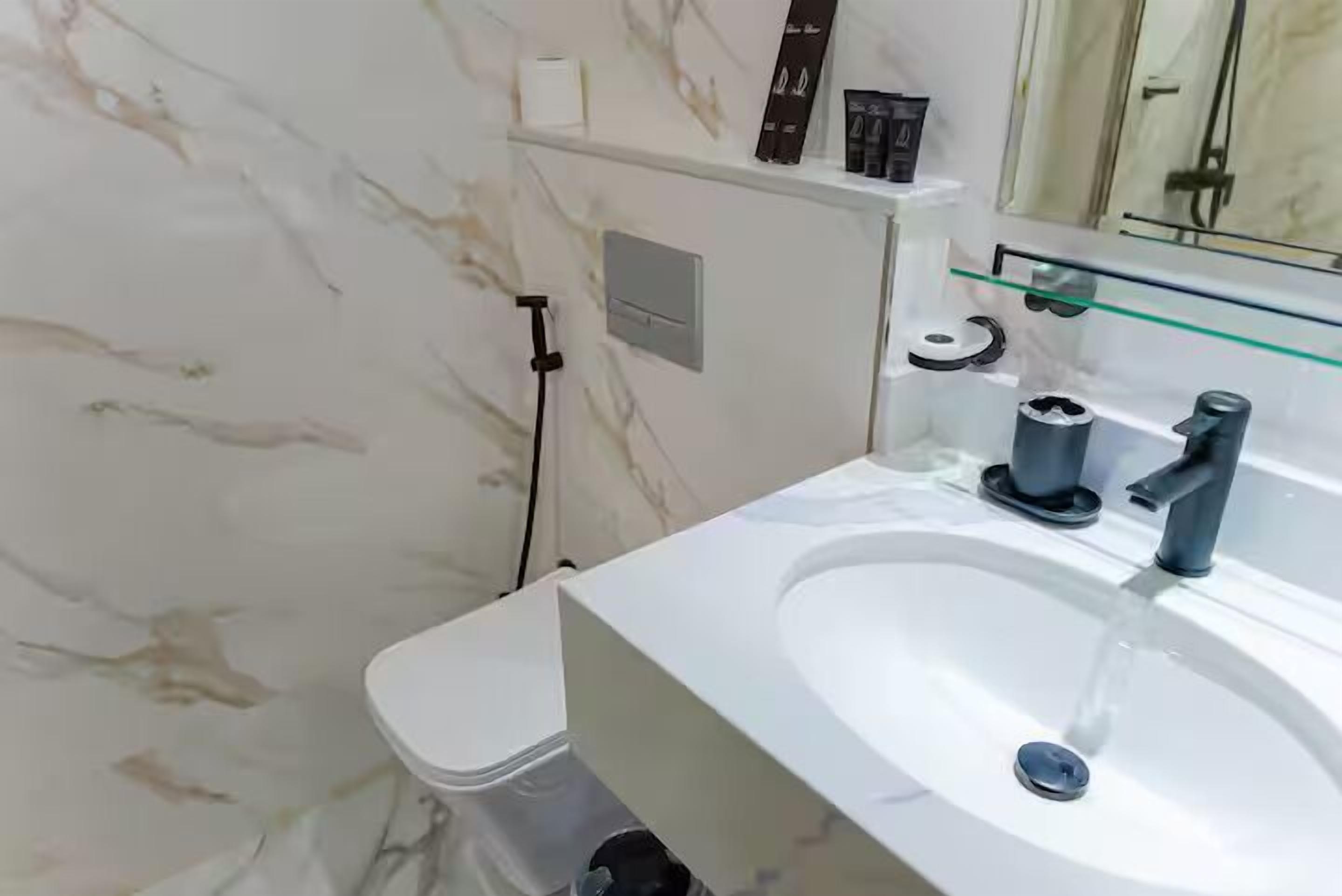 A modern bathroom with a white sink, a mirror, and a toilet.