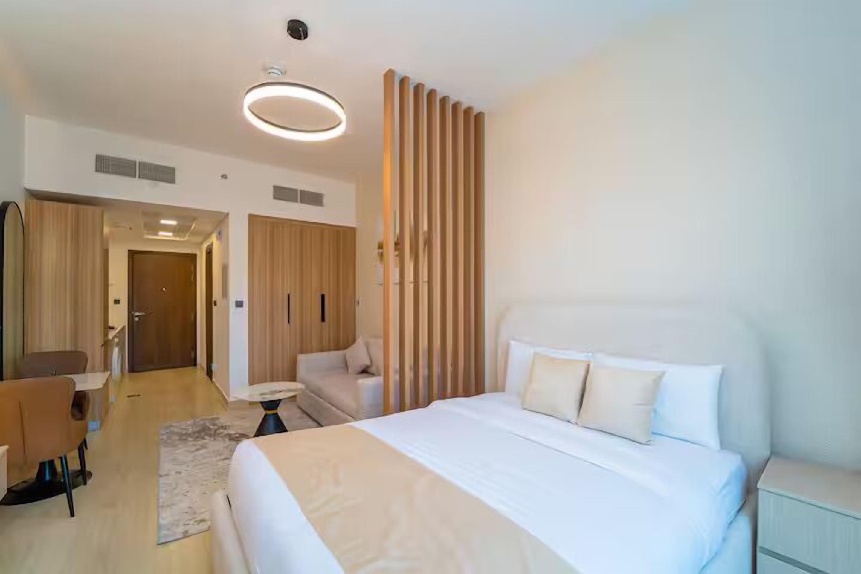 Ein modernes Hotelzimmer mit einem großen Bett, einem Schreibtisch, einem Stuhl und einem Kleiderschrank.