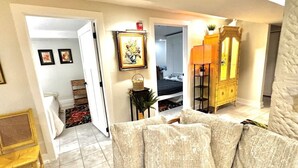 A living room with a sofa, a wooden cabinet, and a door leading to another room. - Tropic Retreat in the heart of The City (Mansfield)