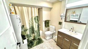 A bathroom with a toilet, sink, and shower curtain. - Tropic Retreat in the heart of The City (Mansfield)
