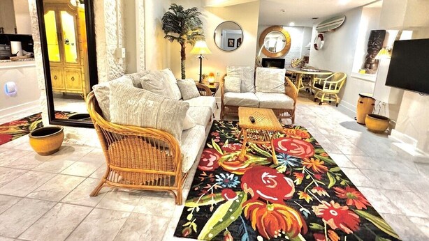 A living room with a sofa, armchairs, a coffee table, and a colorful rug. - Tropic Retreat in the heart of The City (Mansfield)