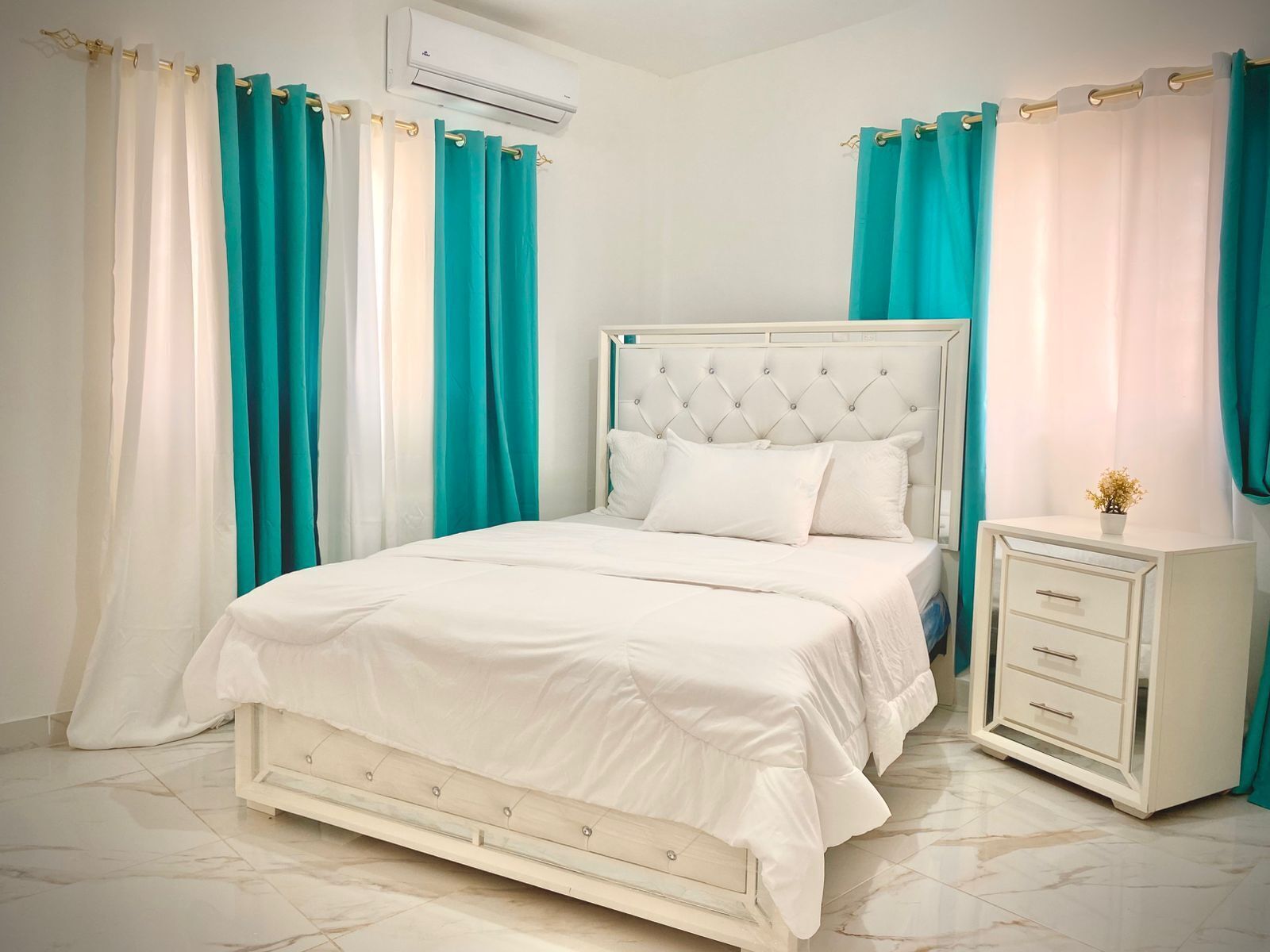 A bedroom with a bed, a nightstand, and curtains.