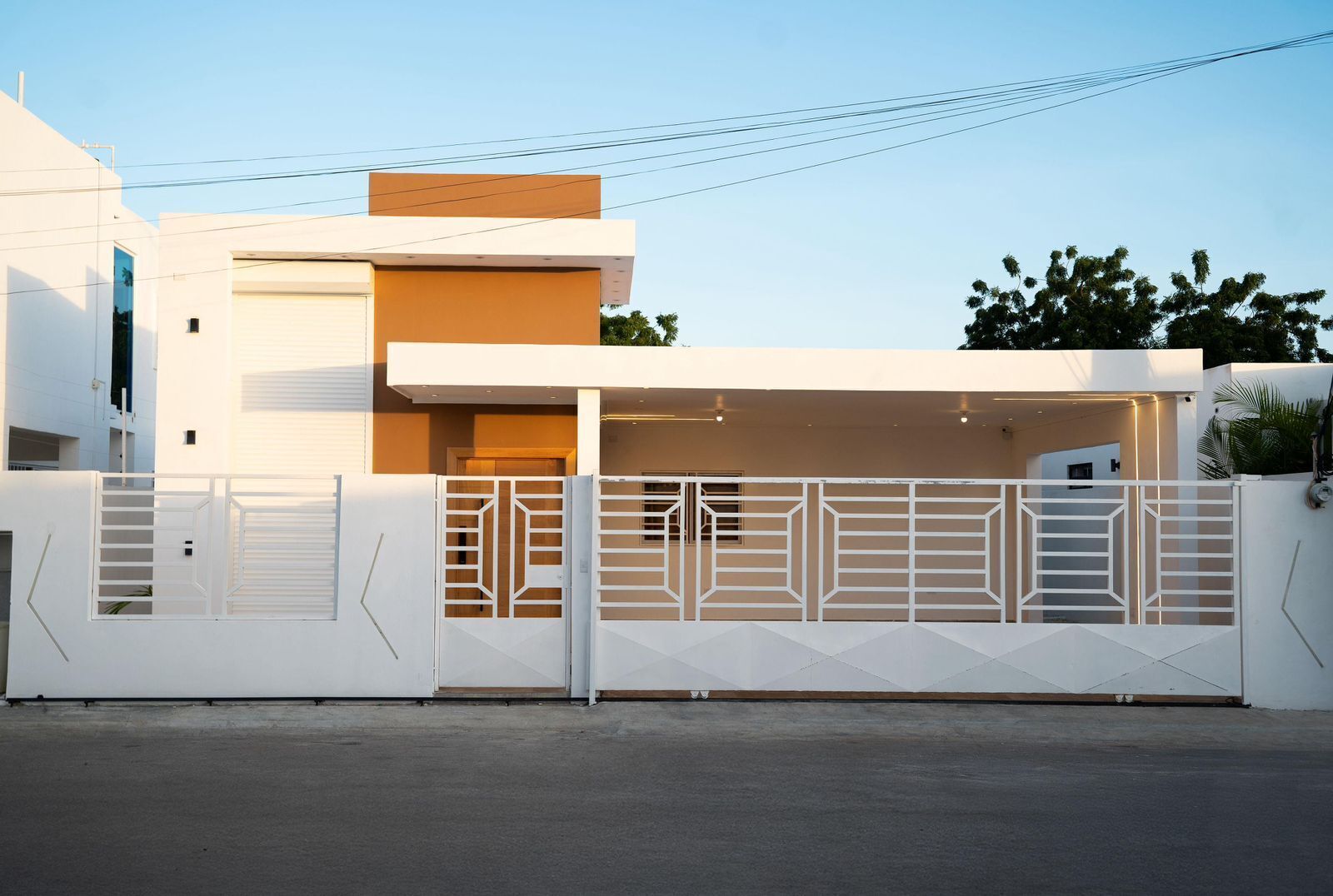 A modern two-story house with a garage, white exterior walls, and a gated driveway.