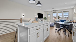 A modern kitchen with a central island, white cabinetry, and pendant lighting. - Island Sunrise Town Home 3 Bdrm/2.5 Bath Sleeps 12!   7 Min walk to the Beach! (Carolina Beach)