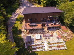 A two-story house with a deck, outdoor seating, and a hot tub.