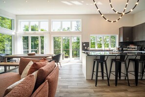 A modern kitchen with a central island, bar stools, and large windows.
