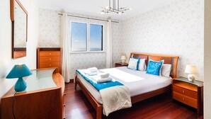 Ein Hotelzimmer mit Bett, Nachttischen, Schreibtisch, Spiegel und einem Fenster mit Vorhängen.