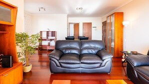 Ein Wohnzimmer mit einer schwarzen Ledersofa, Holzkästen, einem kleinen Tisch und einer Pflanze.