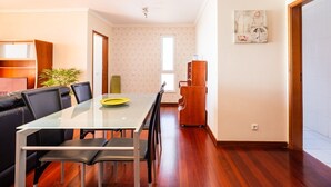 Ein modernes Wohnzimmer mit einem Glastisch, schwarzen Ledersesseln, einer Holzkommode und einem großen Fenster.