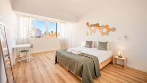 Moderni hotellihuone, jossa on sänky, työpöytä, tuoli ja näkymä ulos.