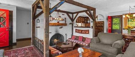 A cozy living room with a wooden ceiling, a fireplace, a sofa, and a table.