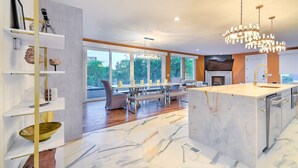 Una cocina moderna con una isla de mármol, un comedor con sillas y un amplio ventanal con vistas al exterior.