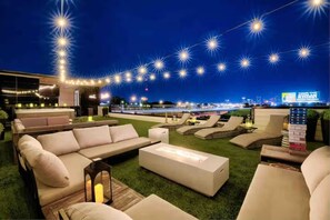 A rooftop lounge area with outdoor seating, string lights, and a view of the city skyline. - Ultra Luxe 16-Bed Mansion w/ Game Room, Large Rooftop Hot Tub, 10 mins from DT! (Nashville)