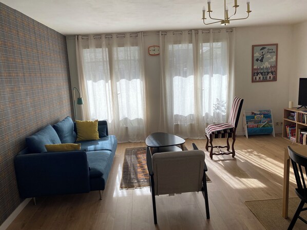 A living room with a blue sofa, a small round table, a striped chair, and a bookshelf. - MAISON GERMÈS - CENTRAL & PRESTIGIOUS (Capacity: 15 people) - Near parking (Bagnères-de-Luchon)