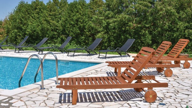 A pool area with lounge chairs and a wooden bench. - Sobe Melada (Trilj)
