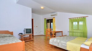 A room with two beds, a desk, a chair, a television, and an air conditioning unit. - Sobe Melada (Trilj)