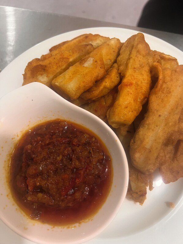 A plate of fried fish and a bowl of sauce. - Celjoe Residence Hotel (Lekki)