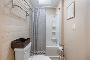 Un baño con ducha, inodoro y un cubo de basura pequeño.