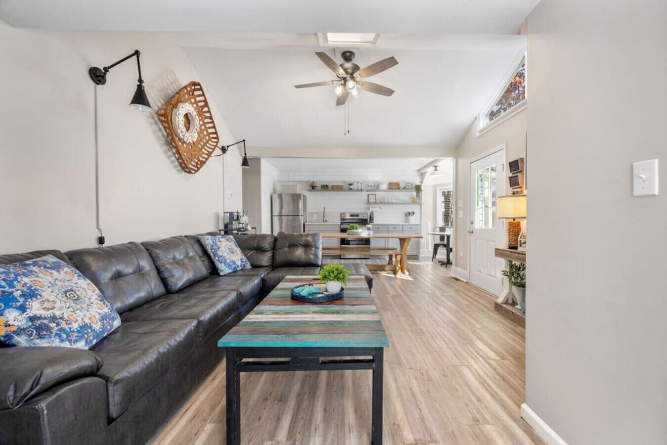 A modern living room with a leather sofa, a wooden coffee table, and a ceiling fan.