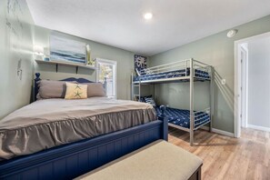 Un dormitorio con una cama litera, una cama individual, una mesita de noche y una ventana con persianas.