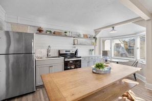 A modern kitchen with white cabinetry, stainless steel appliances, and a wooden island. - Coastal Haven Getaway, Beach Stay & Resort Perks! (Myrtle Beach)