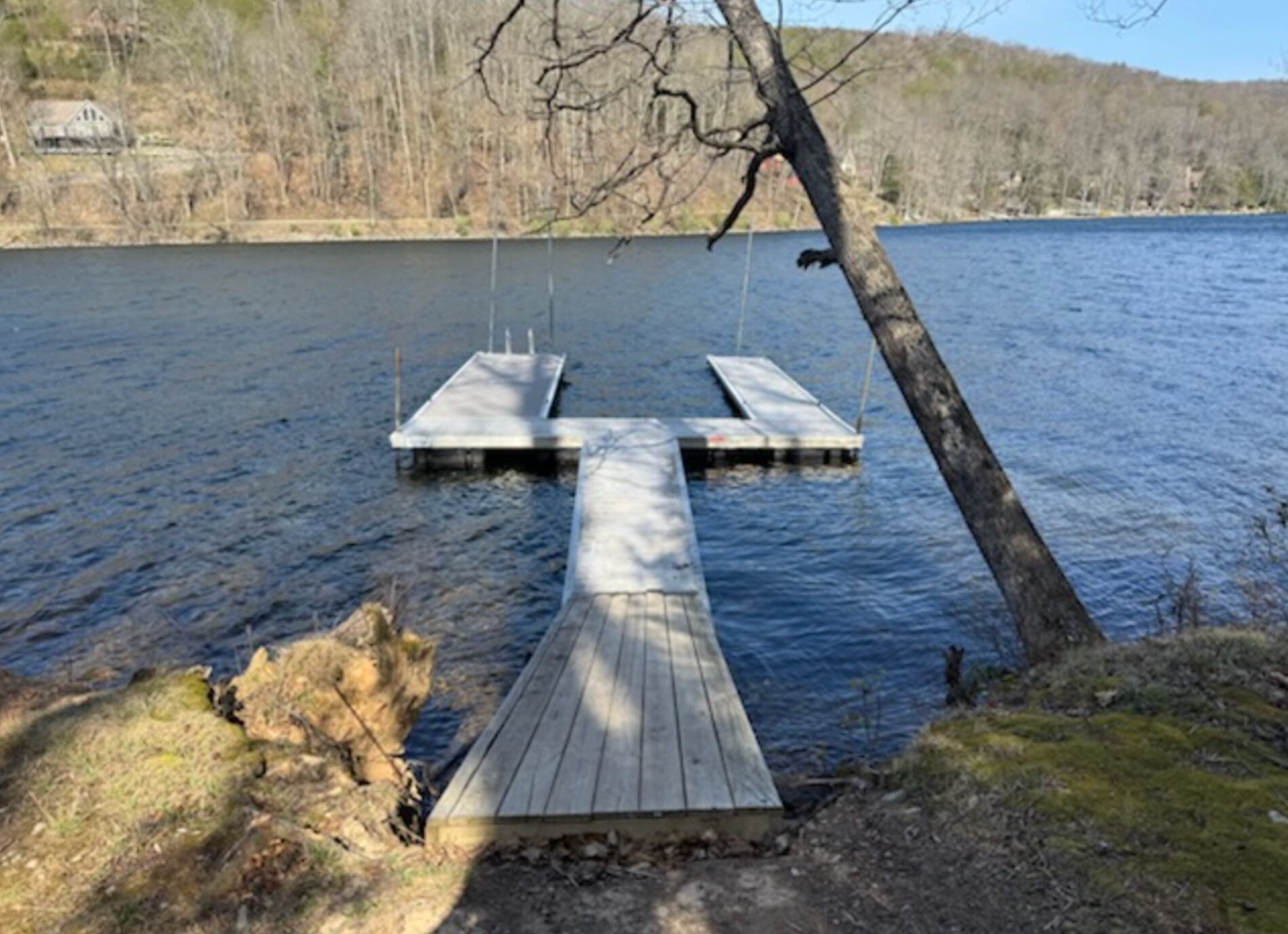 A wooden dock extending into a calm lake with a forested shoreline in the background.