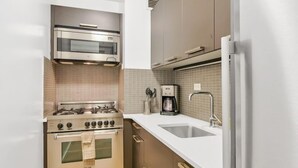 Una cocina moderna con electrodomésticos de acero inoxidable, horno empotrado, cafetera y un lavamanos.