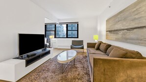 Una sala de estar moderna con un televisor de pantalla plana, una mesa de centro, un sofá y un cuadro en la pared.