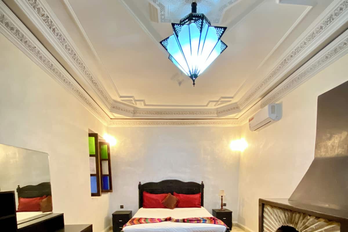 Une chambre à coucher avec un lit, une télévision, une cheminée et un sol à motifs.
