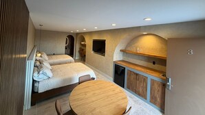 A modern bedroom with a bed, a desk, and a small dining table. - Presidio Inn (Presidio)