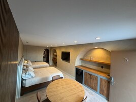 Un dormitorio moderno con cama, escritorio y una pequeña mesa de comedor.