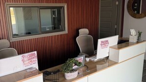 A reception desk with a wooden panel wall, a large window, and a round mirror on the wall. - Presidio Inn (Presidio)