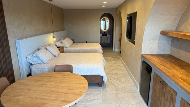 A modern hotel room with two beds, a dining table, and a kitchen area. - Presidio Inn (Presidio)