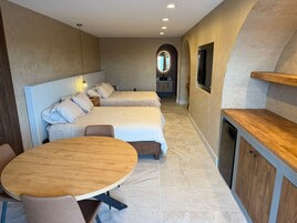 Una habitación de hotel moderna con dos camas, una mesa de comedor y una cocina.