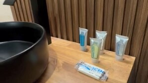 A wooden vanity with a black basin, three toiletry tubes, and a facial cleansing product. - Presidio Inn (Presidio)