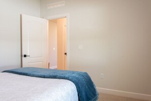 A bedroom with a bed, a door, and a light switch on the wall. - St. Augustine 3BR | Near Downtown & Beaches (St. Augustine)