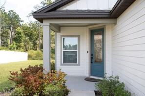 A house with a front porch, a blue door, and a small garden area. - St. Augustine 3BR | Near Downtown & Beaches (St. Augustine)