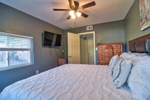 A bedroom with a bed, a ceiling fan, a dresser, a television, and a door. - Enjoy 3-Bedroom House with AC, Heated Pool and Gazebo in Charming Pinellas Park (Pinellas Park)