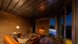 Una sala de estar moderna con un sofá de cuero, una mesa de centro, una chimenea y un televisor.