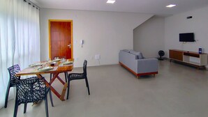 Ett modernt vardagsrum med en matplats, en soffa, en tv och en dörr.