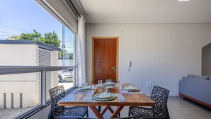 En matplats med ett träbord dukat för fyra personer, omgiven av svarta stolar, en grå soffa och en trädörr.