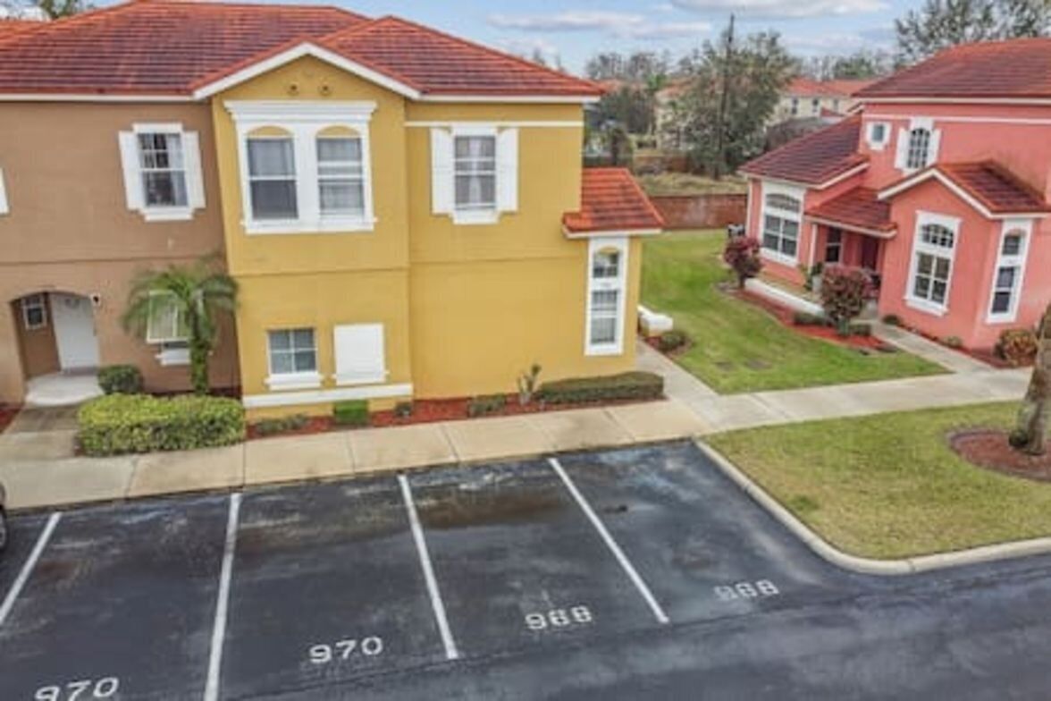 A residential area with a yellow house and a red house. There are parking spaces marked with numbers.